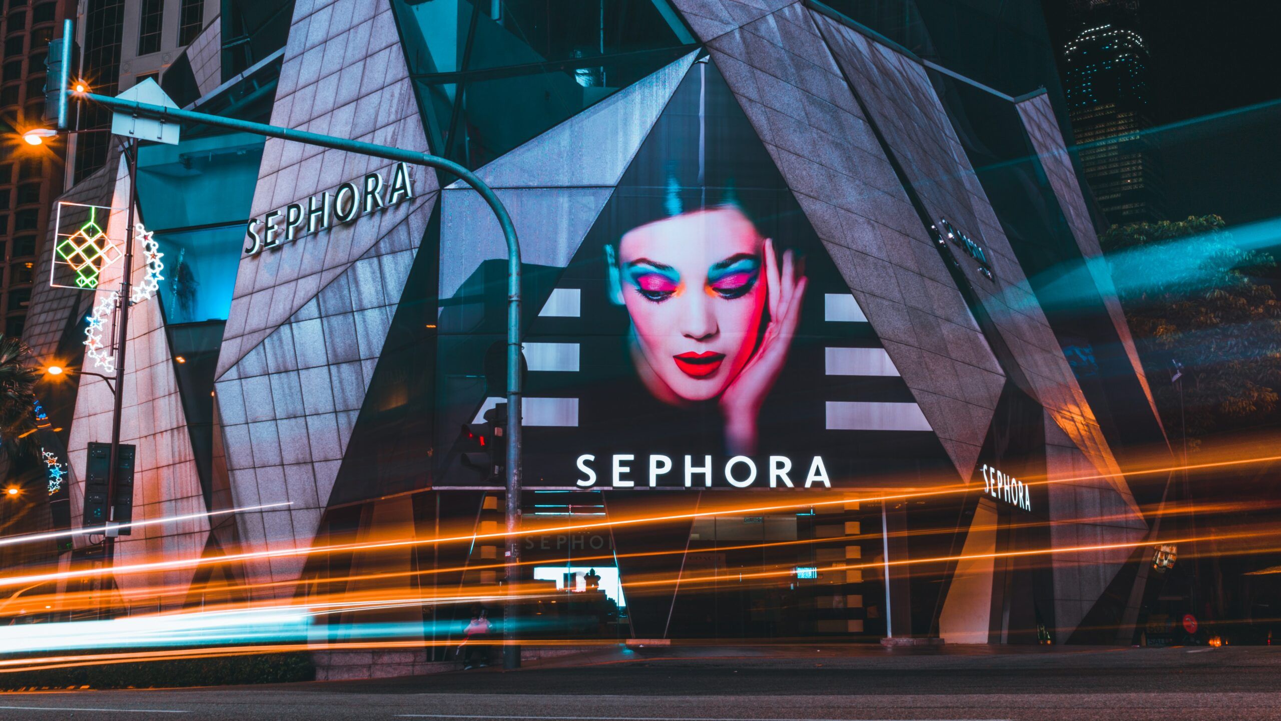 A Sephora store at night with neon lights and a photo of a female model wearing makeup