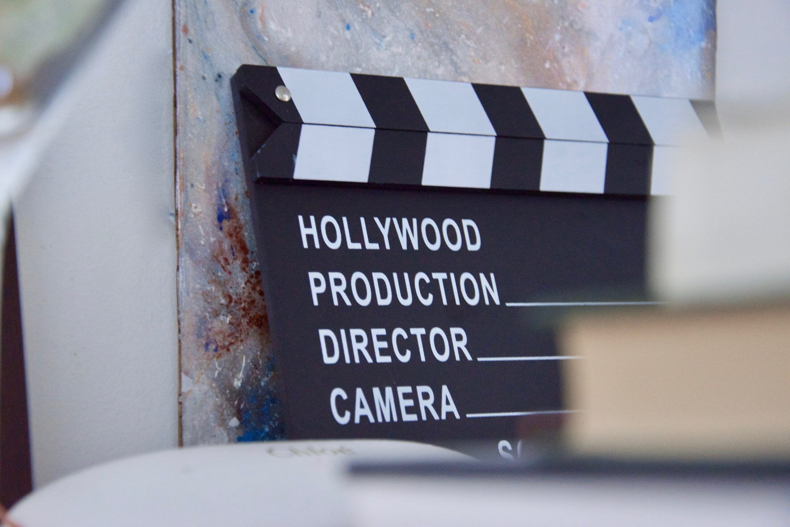 Black and white clapper board with writing that says Hollywood, Production, Director, Camera