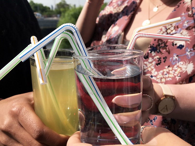 people holding three glasses with coloured drinks and plastic straws