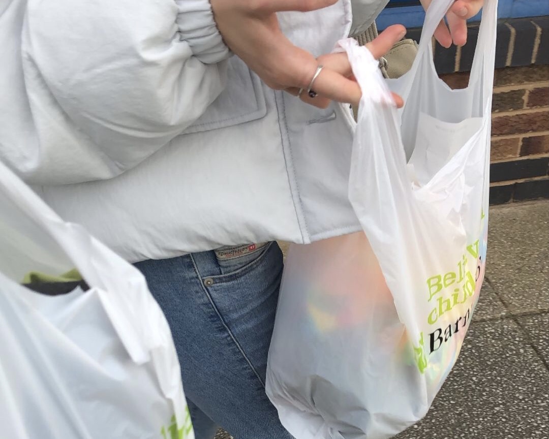 Woman holding charity shop plastic bag of clothing