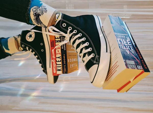 Martina's bookstagram bookshelf pic with a shot of books balanced on her trainers