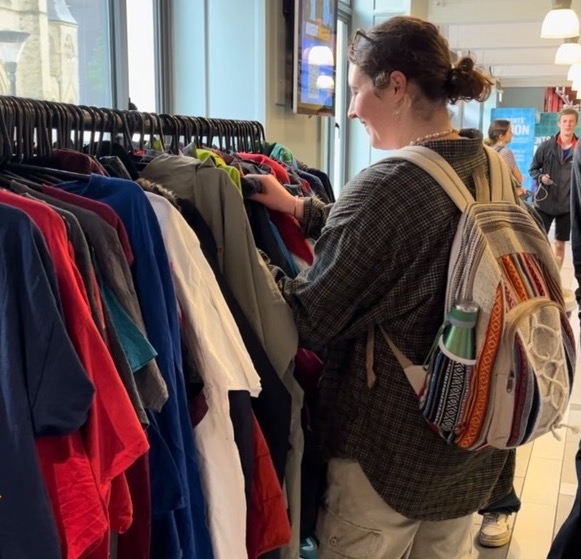 A person looking through clothes on a clothing rail 