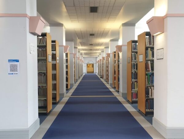 A photo depicting a library corridor with bookshelves on both sides of the path